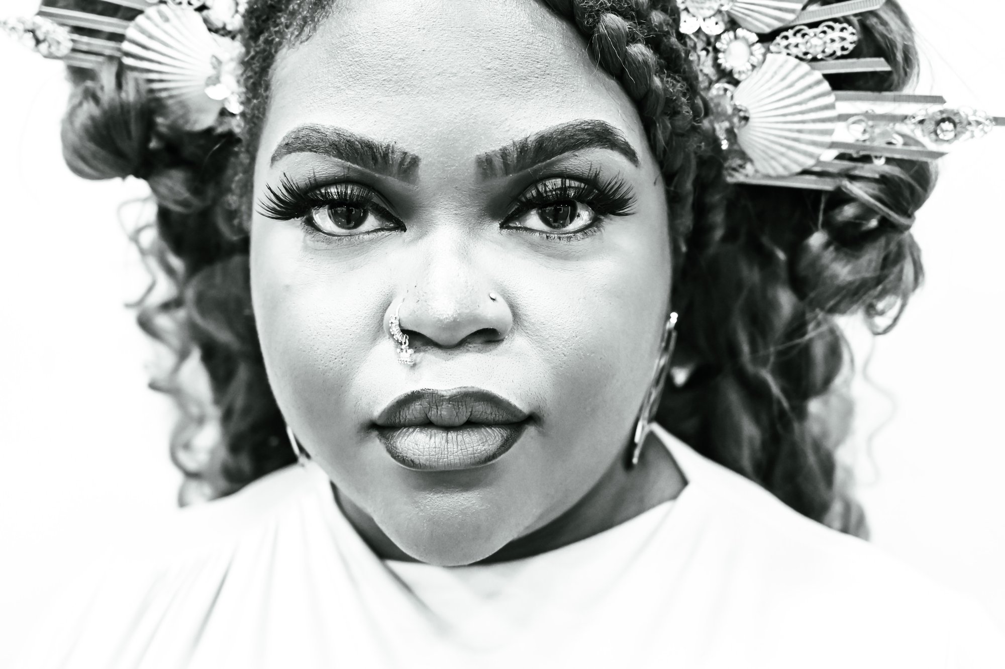 Black-and-white close-up editorial portrait — Jess Kelly with ornamented hair and bold lashes